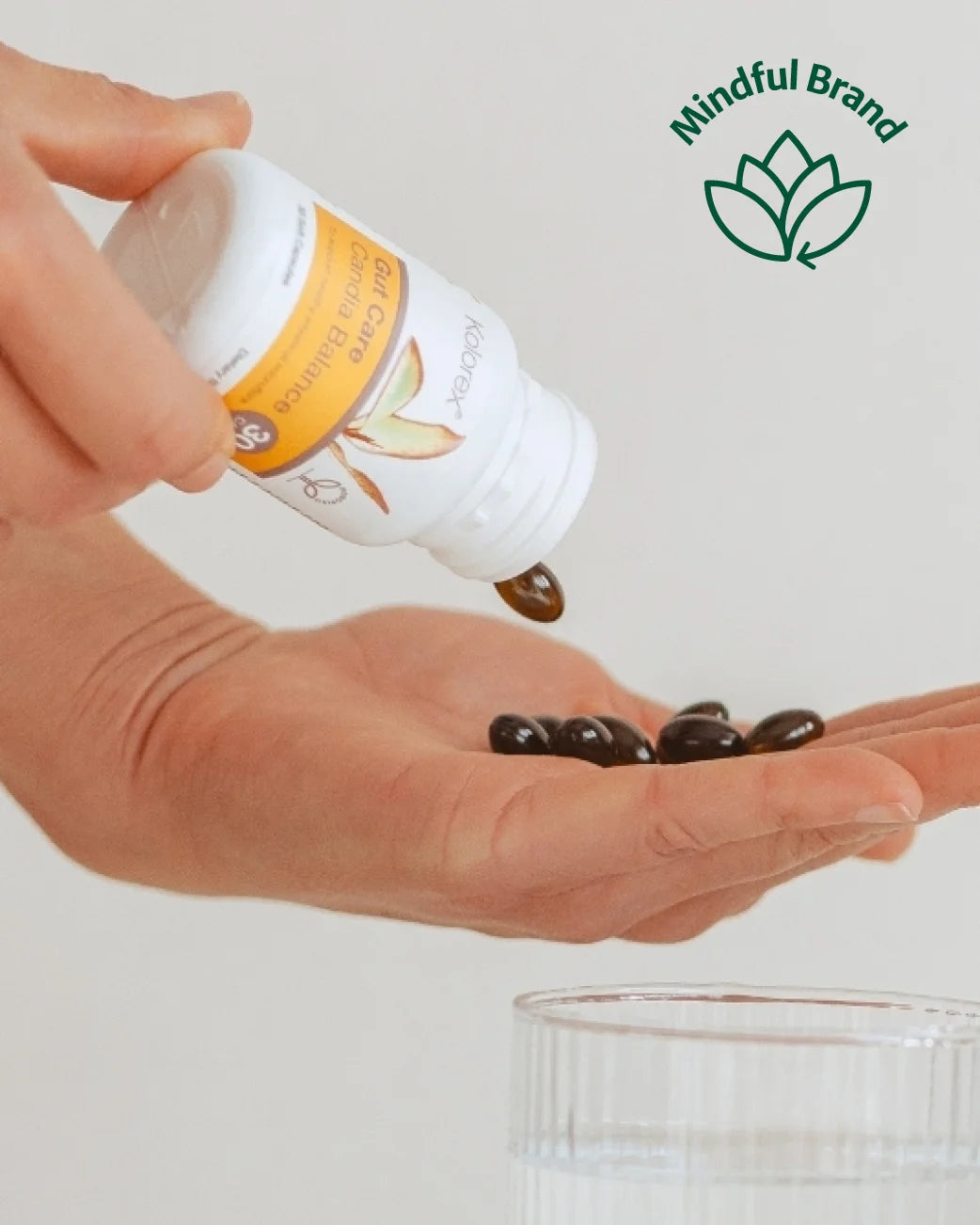 Hand pouring capsules from a bottle labeled 'Mindful Brand' onto a palm.