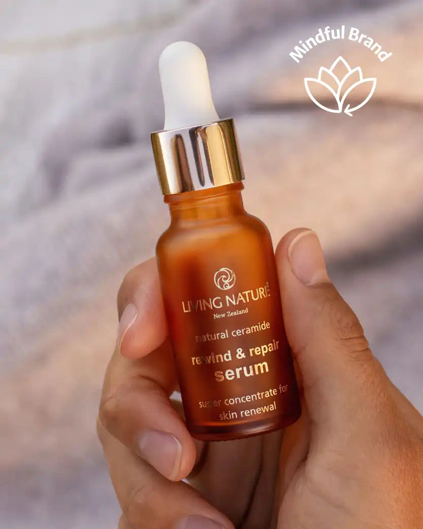 Hand holding a Living Nature serum bottle with a blurred background.