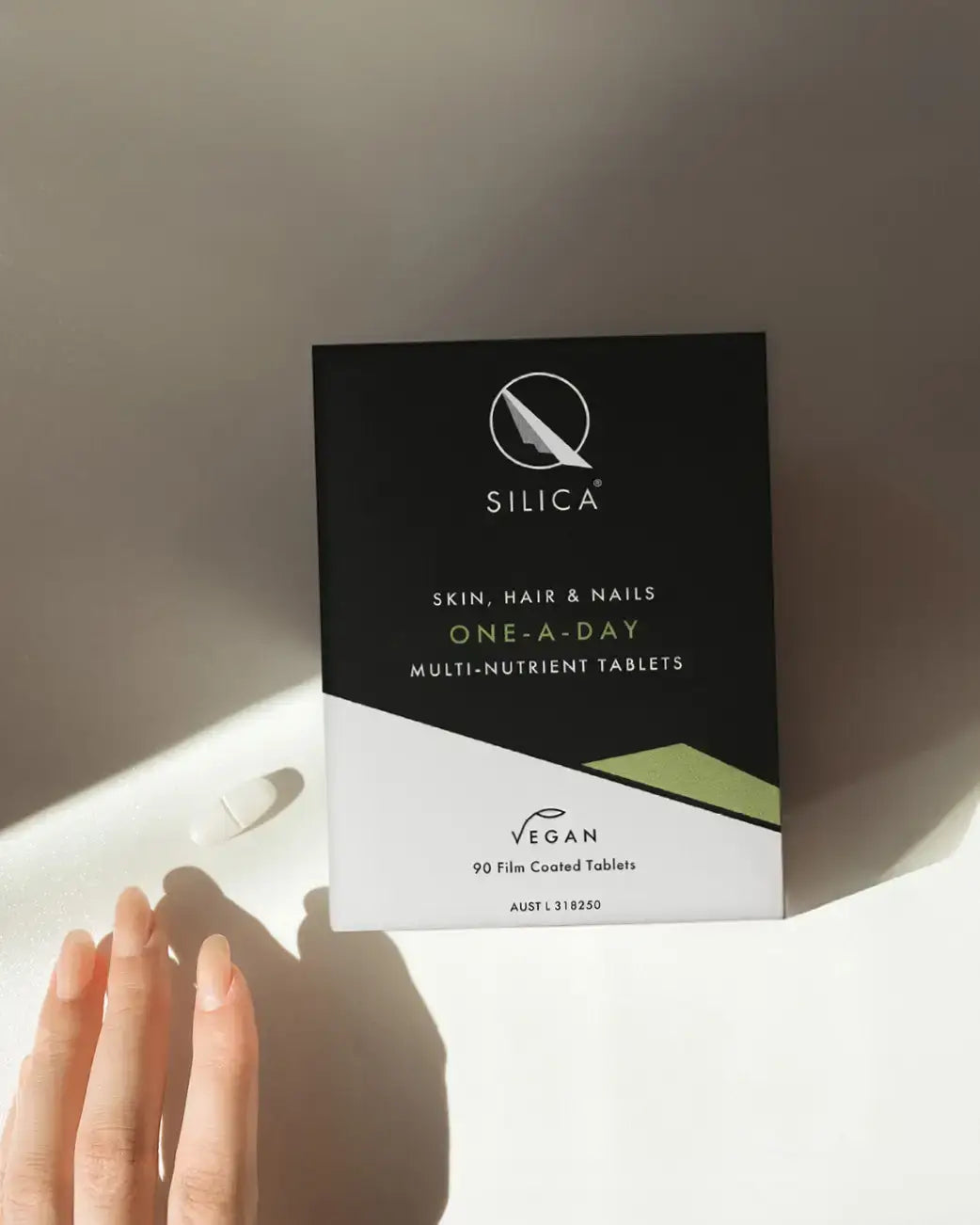 Silica multi-nutrient tablets packaging on a light surface with a hand holding a tablet.