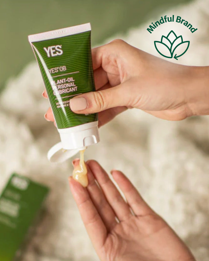 Hand holding a tube of YES OB personal lubricant with 'Mindful Brand' logo in the corner.