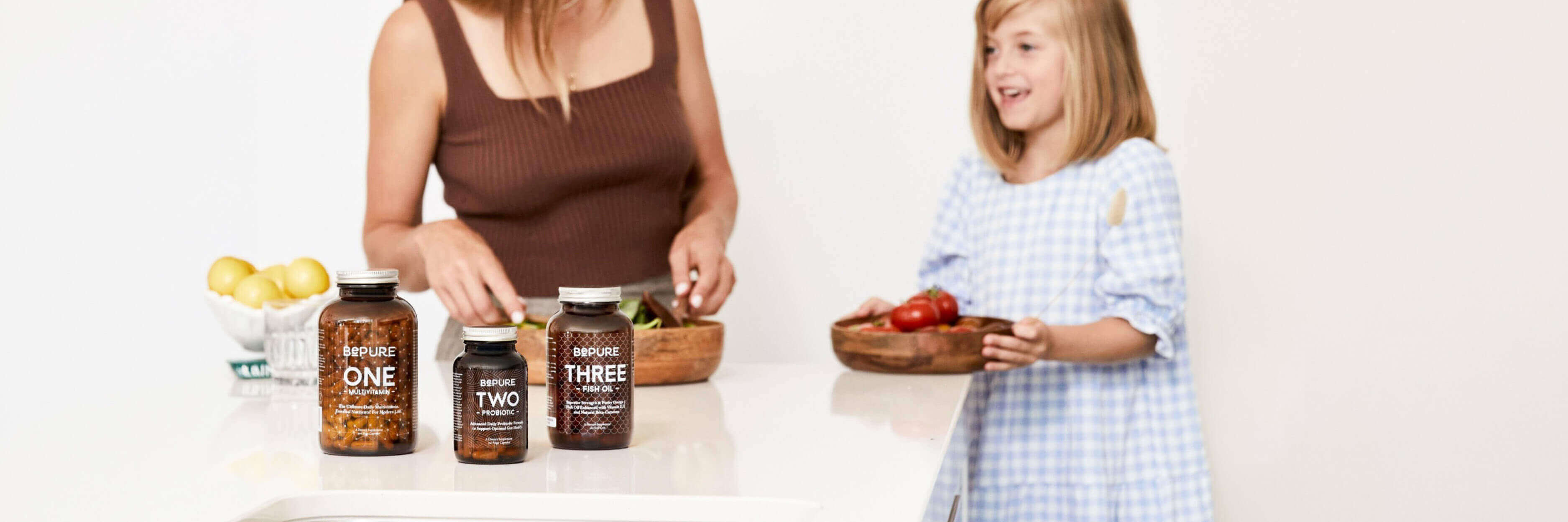 Woman and child in a kitchen with bottles labeled 'Pure One', 'Pure Two', and 'Pure Three'.