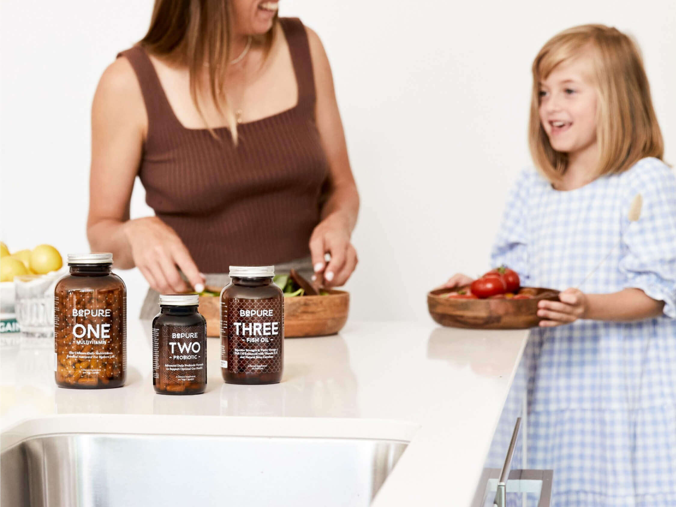 Woman and child in a kitchen with bottles labeled 'Pure One', 'Pure Two', and 'Pure Three'.