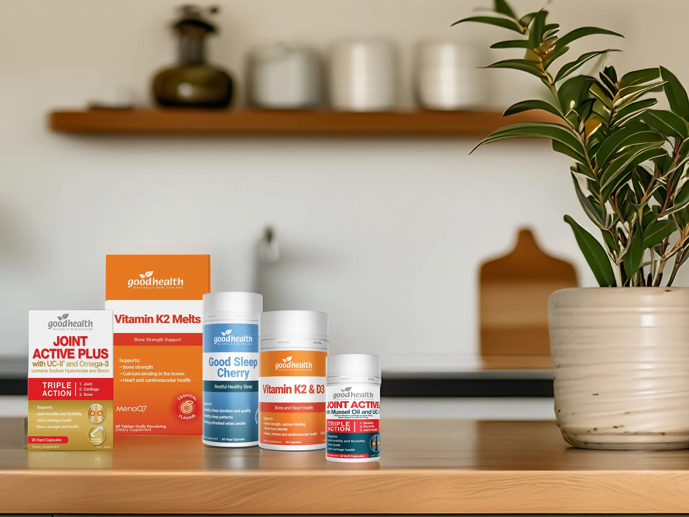 Collection of Good Health supplement products on a wooden surface next to a plant.