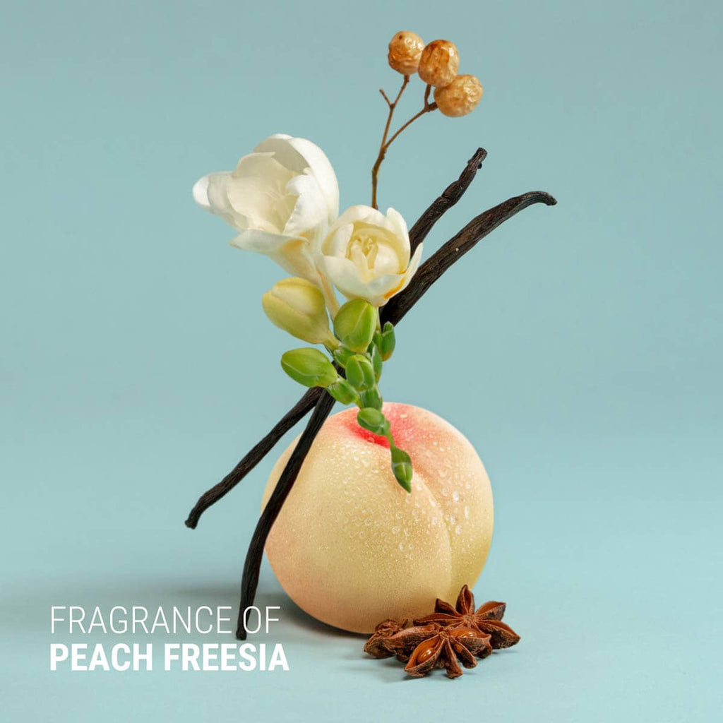 Bath bomb with vanilla bean, peach, and flowers on a light blue background.