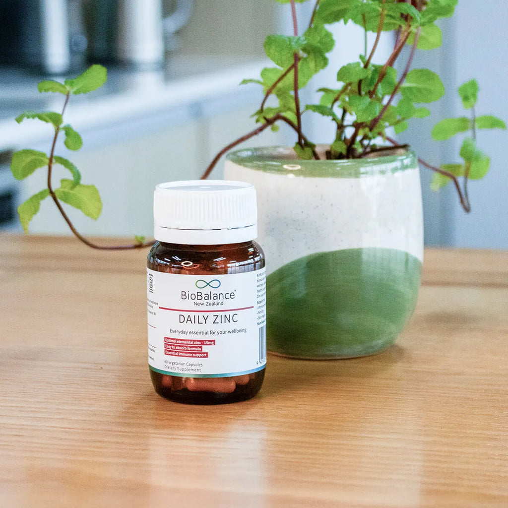 BioBalance Daily Zinc supplement bottle on a wooden surface with a plant in the background.