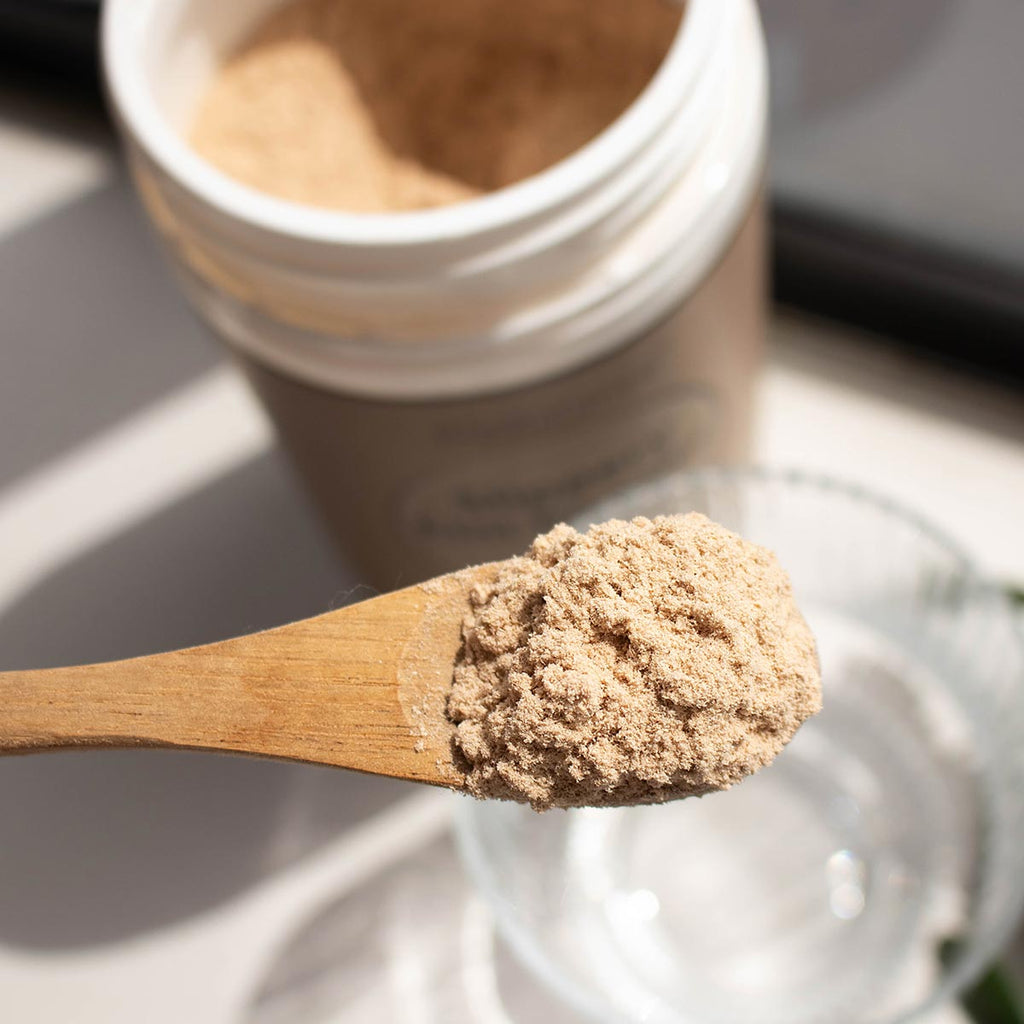 Wooden spoon with slippery elm powder ready to be stirred into a glass of water.