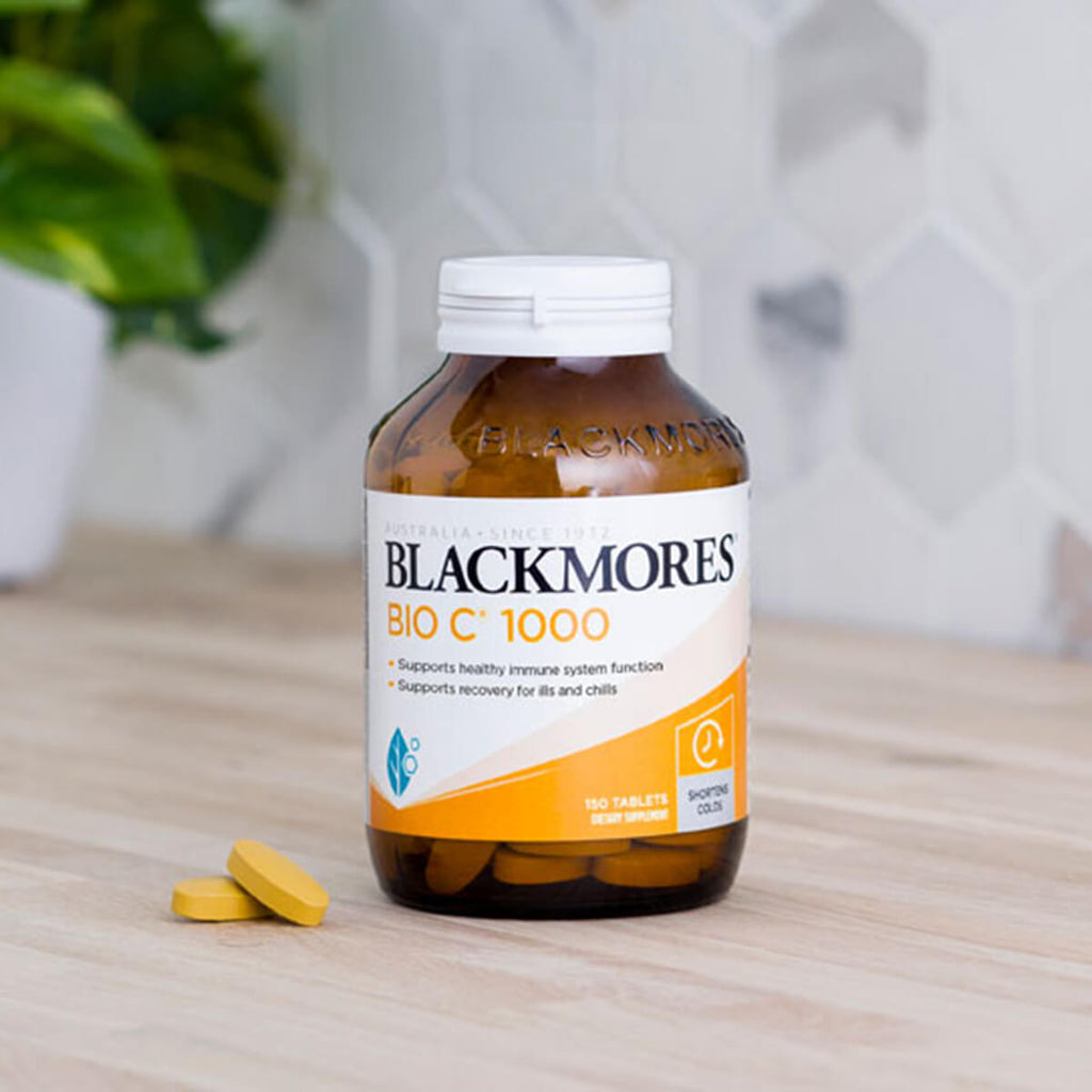 Blackmores Bio C 1000 supplement bottle on a wooden surface with a blurred background.