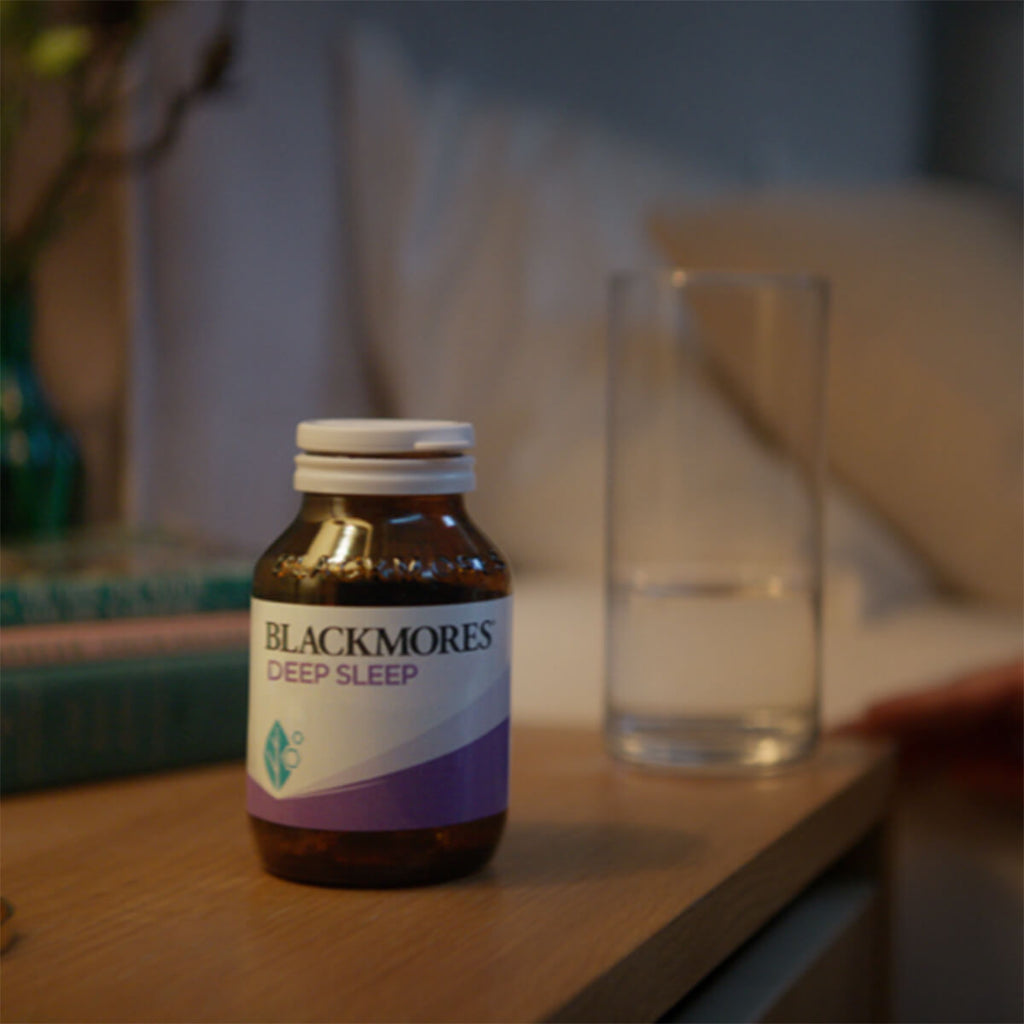 Blackmores Deep Sleep supplement bottle on a wooden surface with a blurred background.