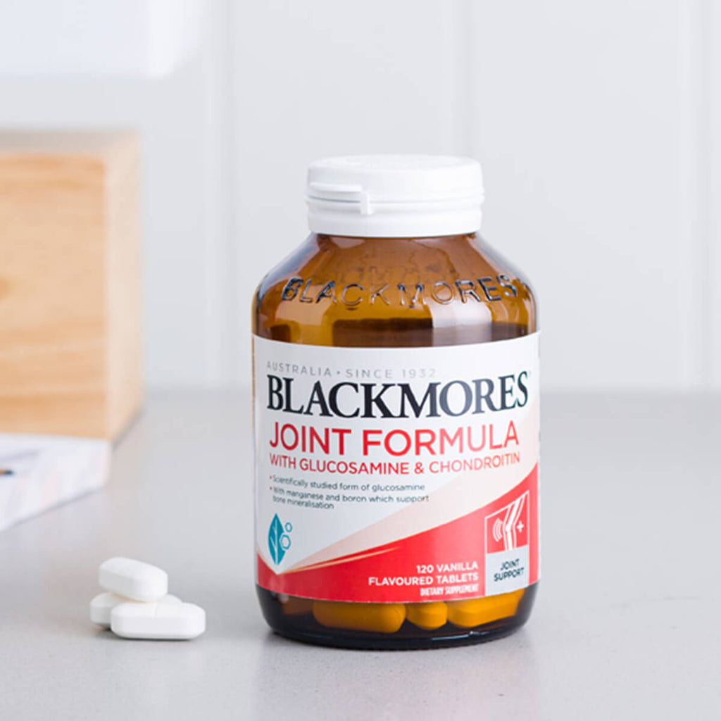 Blackmores Joint Formula bottle on a white surface with tablets beside it.