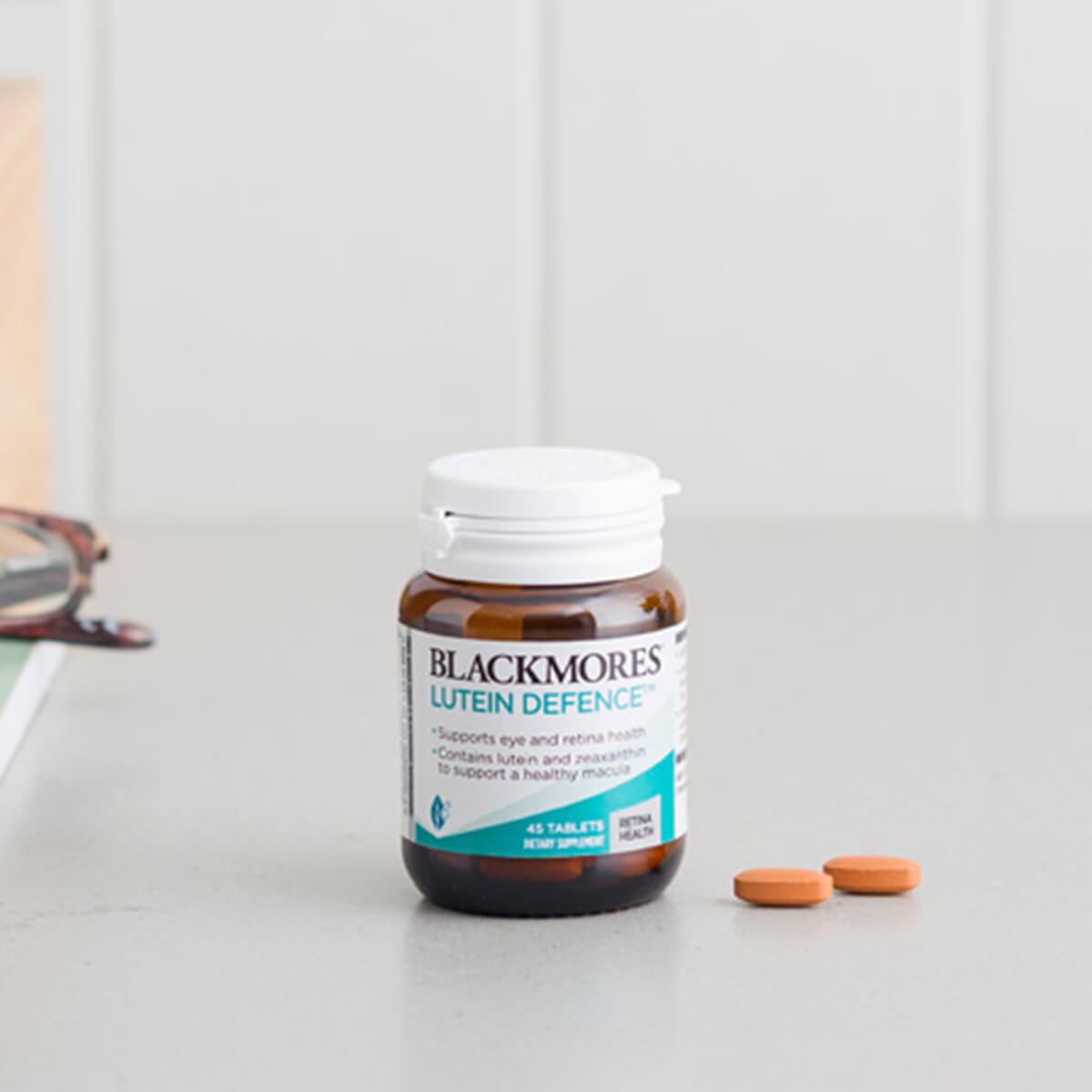 Blackmores Luten Defence supplement bottle with two tablets on a light gray background.