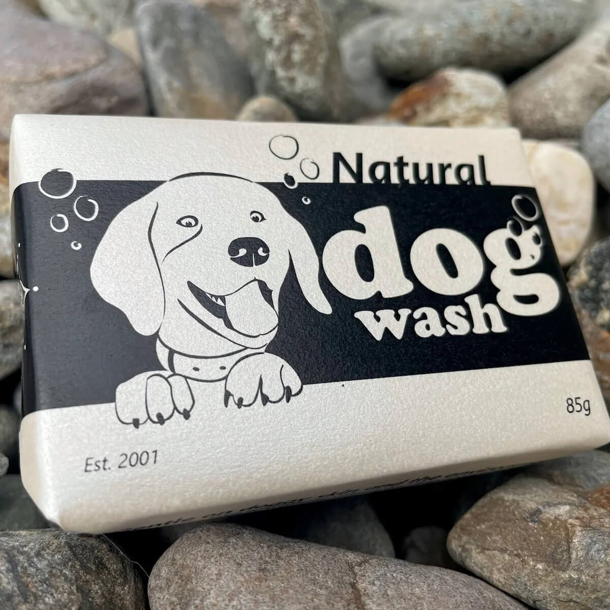 Bar of soap labeled 'Natural Dog Wash' with a cartoon dog on a background of stones.