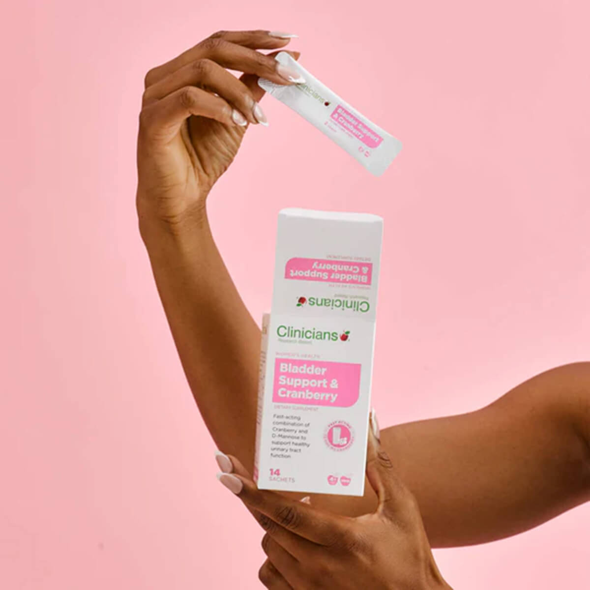 Hand holding Clinicians Bladder Support & Cranberry product against a pink background.