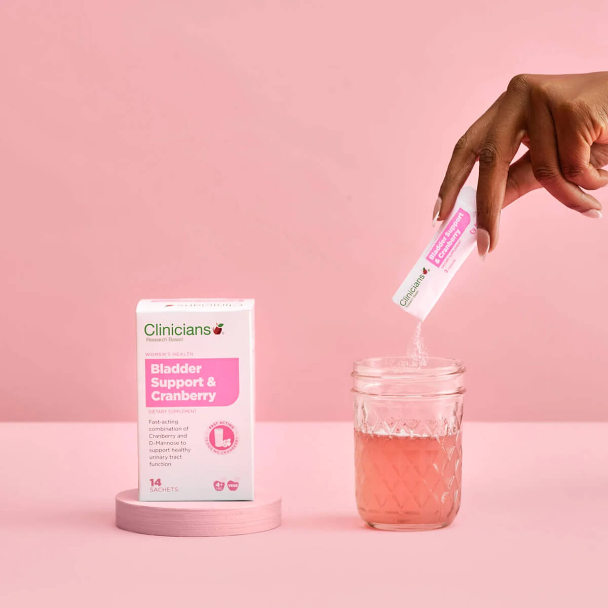 Clinicians Bladder Support & Cranberry product with a hand pouring a pink liquid into a jar on a pink background.