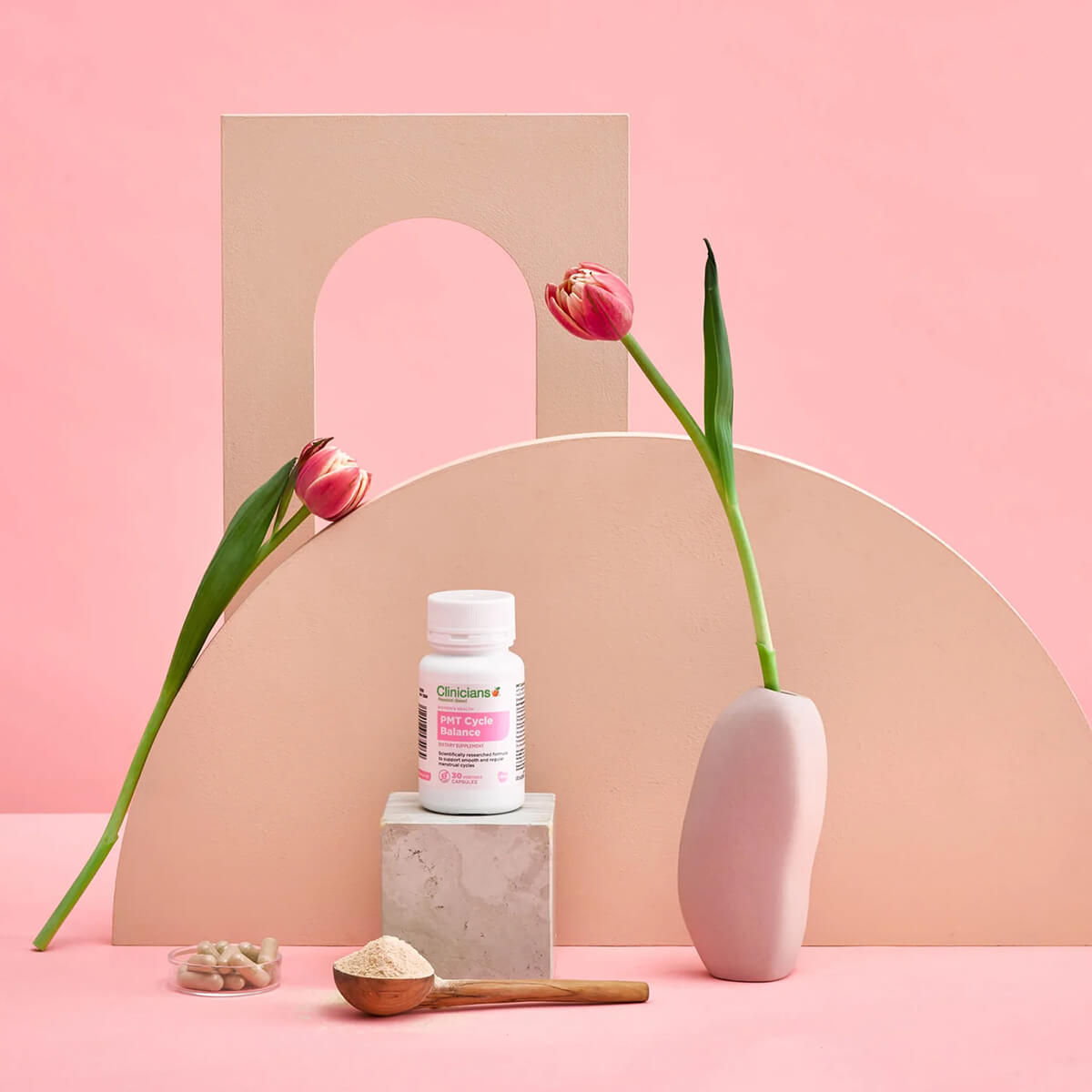 Product bottle with pink label on a geometric pink and beige background with tulips and a vase.