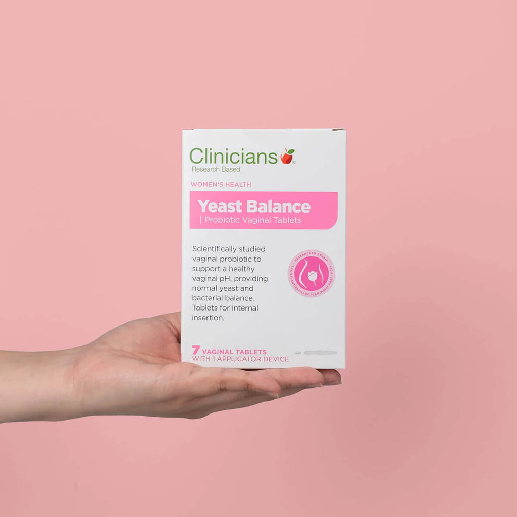 Clinicians Yeast Balance Probiotic Vaginal Tablets packaging held in a hand against a pink background.