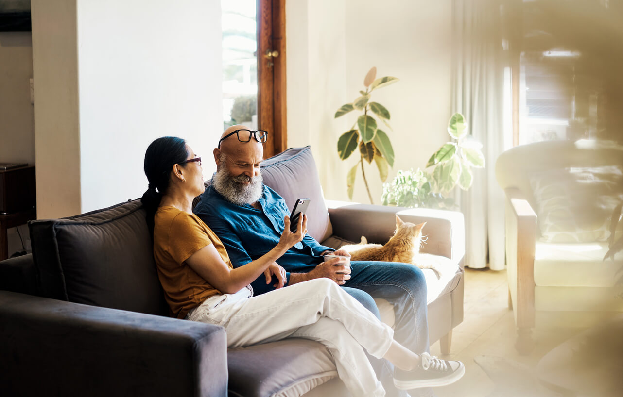 Couple sitting on a couch looking at a phone.