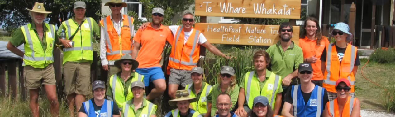 Group of volunteers wearing high vis vests in front of the HealthPost Nature Trust sign.
