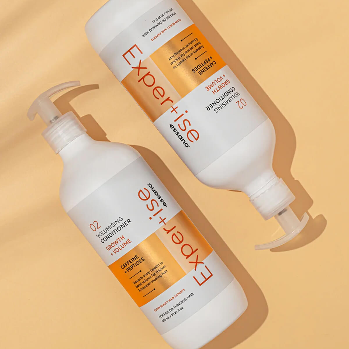 Two bottles of 'Expertise' hair care products on a beige background.