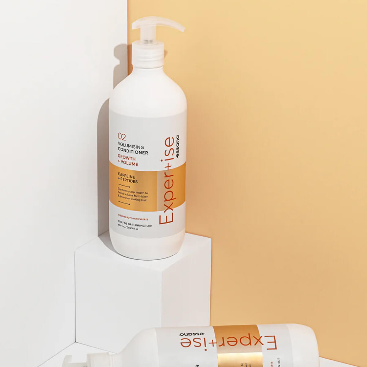 White bottle of 'Expert+ise' hair care product on a light background.