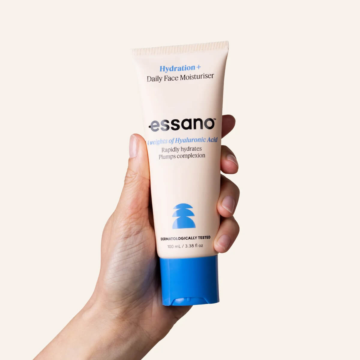 Hand holding a tube of essano daily face moisturizer against a white background.