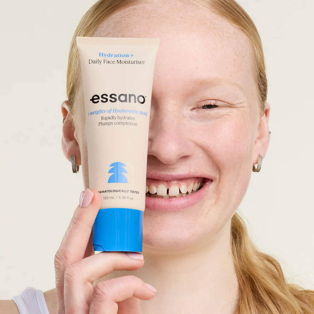 Person holding a tube of essano daily face moisturiser against a plain background.