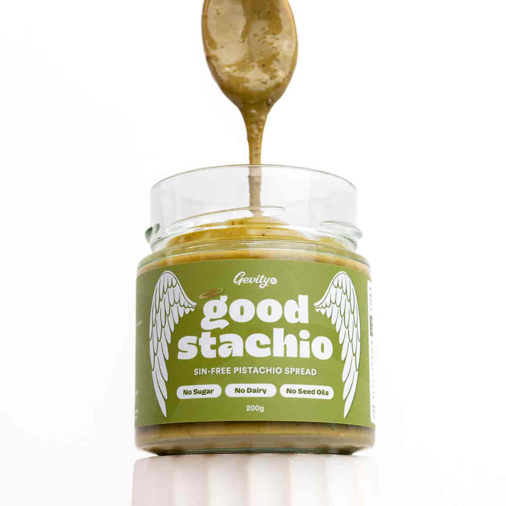 Jar of 'good stachio' pistachio spread with a spoonful being lifted out, on a white background.