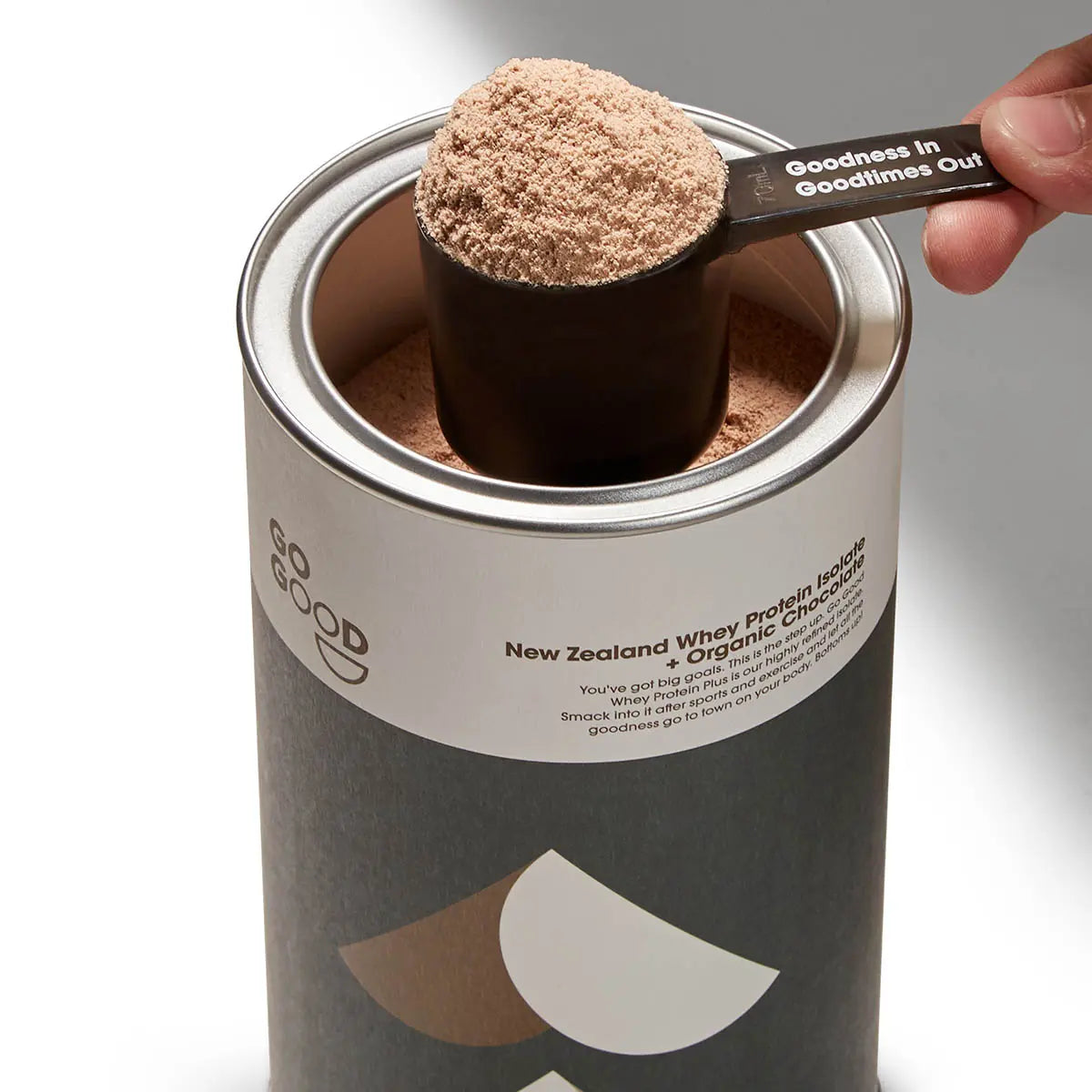 Person taking a scoop of Go Good Whey Protein Isolate out of the container ready to add to blender.