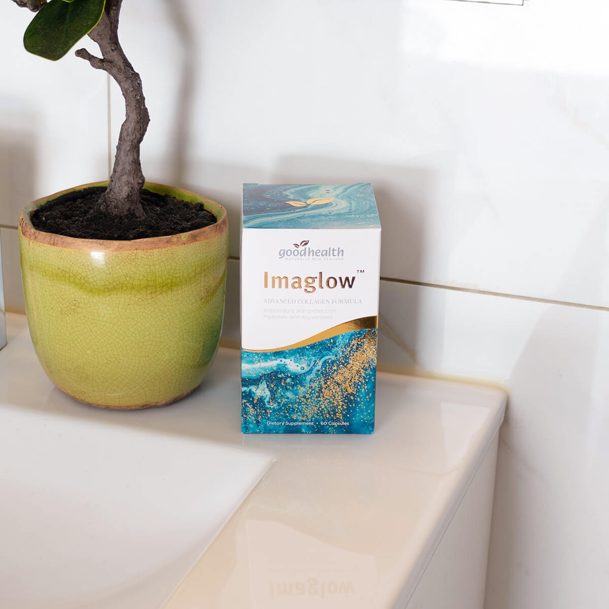 Box of 'Imaglow' on a surface with a potted plant in the background.