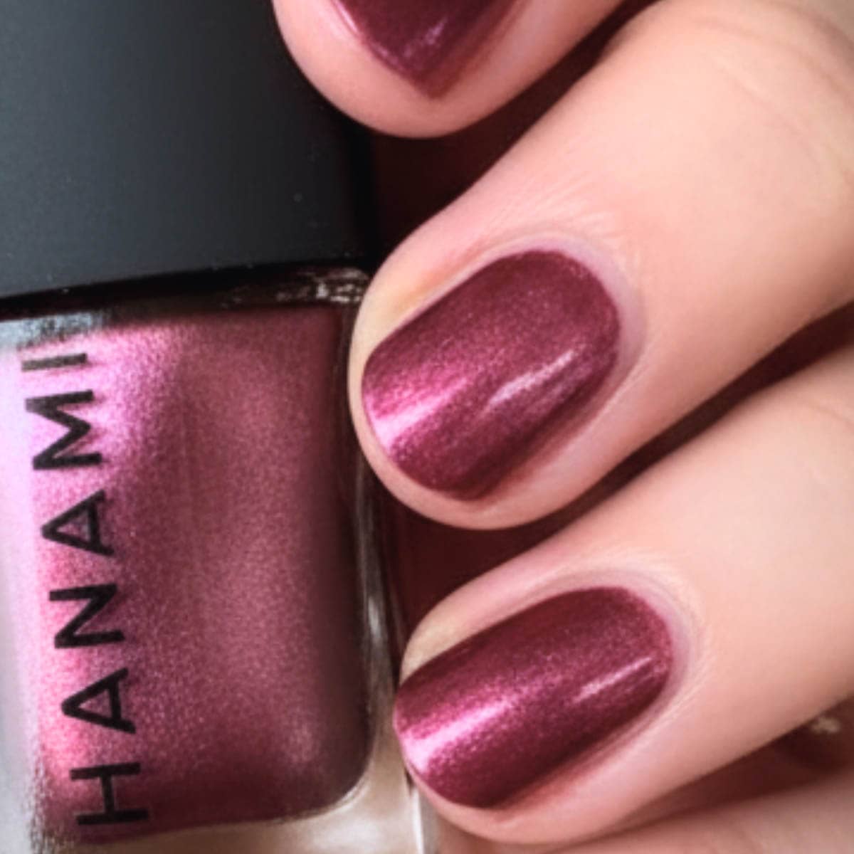 Close-up of a hand with purple nail polish matching a Hanami nail polish bottle.