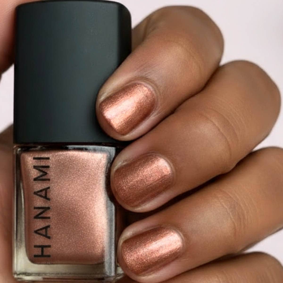 Nail polish with a metallic finish held by a hand, brand 'HANAMI' visible.