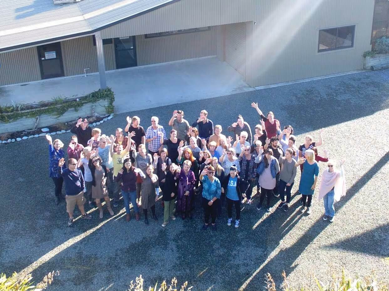 Collingwood staff pictured in front of office building, waving and smiling up at camera.