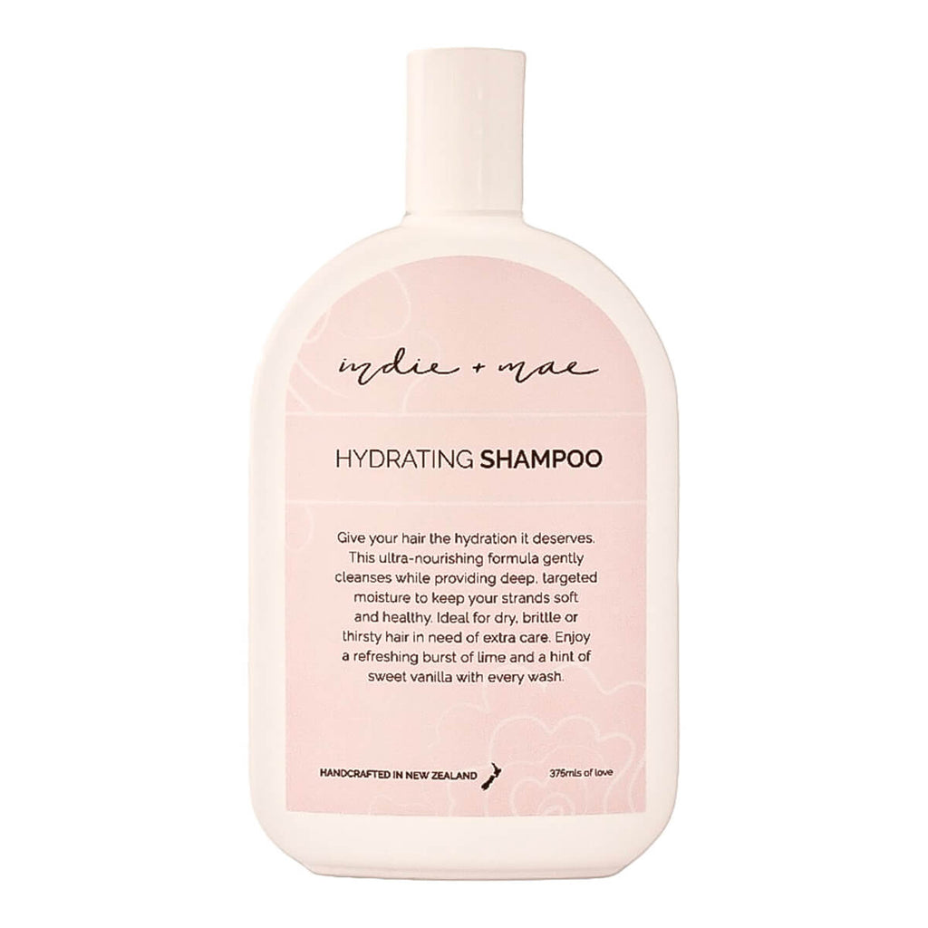 A bottle of Indie + Mae Hydrating Shampoo, featuring a soft pink and white design with black text.