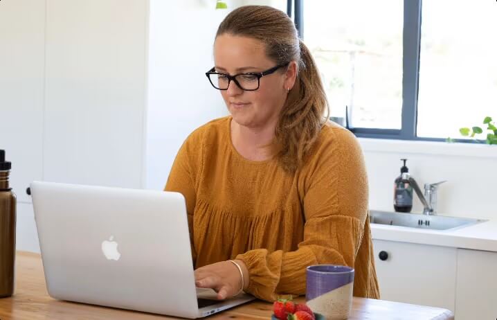 Woman shopping on her laptop on a dining table.