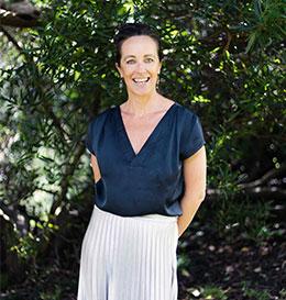 Woman standing outdoors with greenery in the background