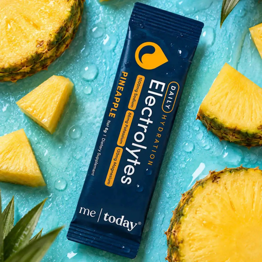 Sachet of pineapple electrolytes on a blue background with pineapple pieces.