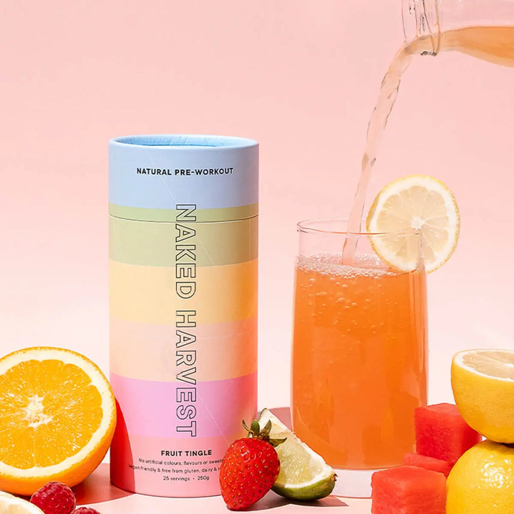 Naked Harvest natural pre-workout supplement container and drink in a glass with fresh fruits on a pink background.