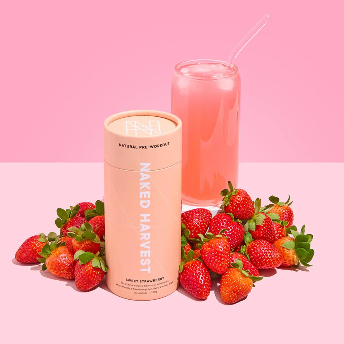 Naked Harvest pre-workout supplement container with strawberries and a pink drink on a pink background