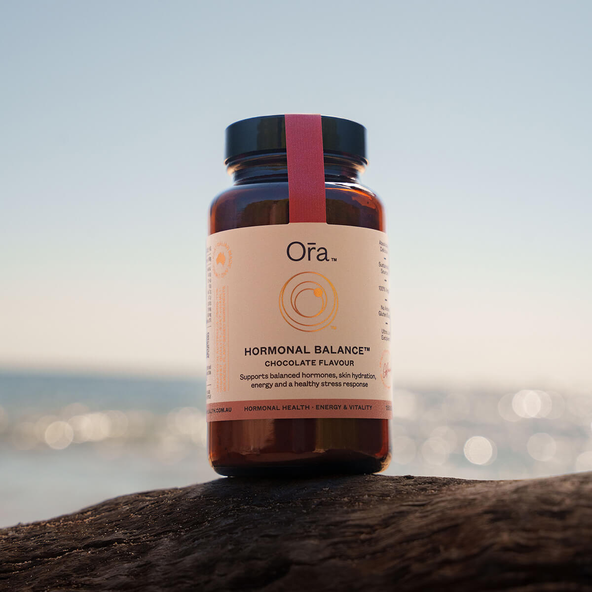 Ora Hormonal Balance supplement bottle on a wooden surface with a blurred natural background