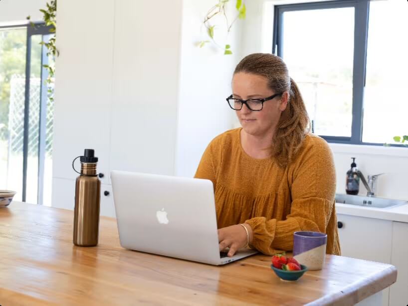 Woman with glasses typing on a laptop.