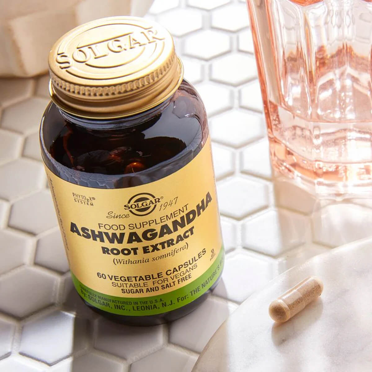 Solgar Ashwagandha supplement bottle next to a capsule on a tiled surface.