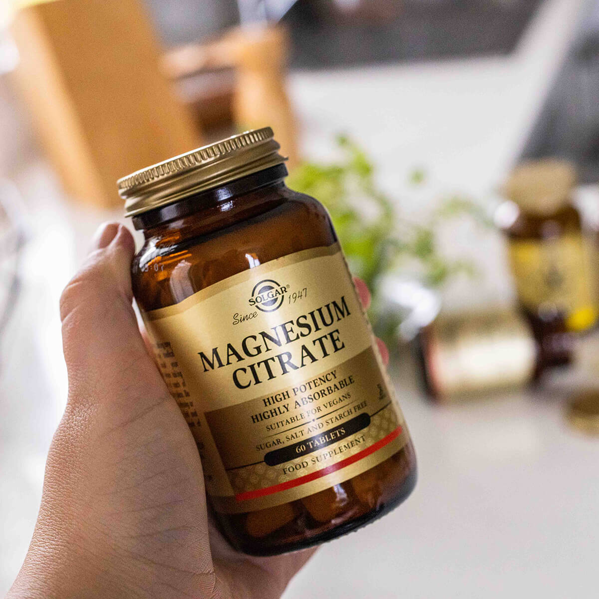 Hand holding Magnesium Citrate supplement bottle.