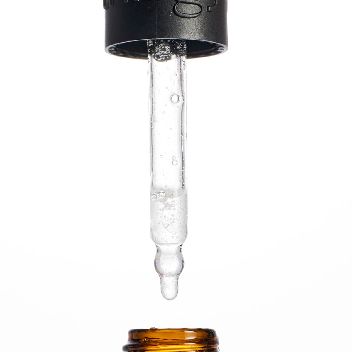 Close-up of a dropper with liquid being dispensed on a white background