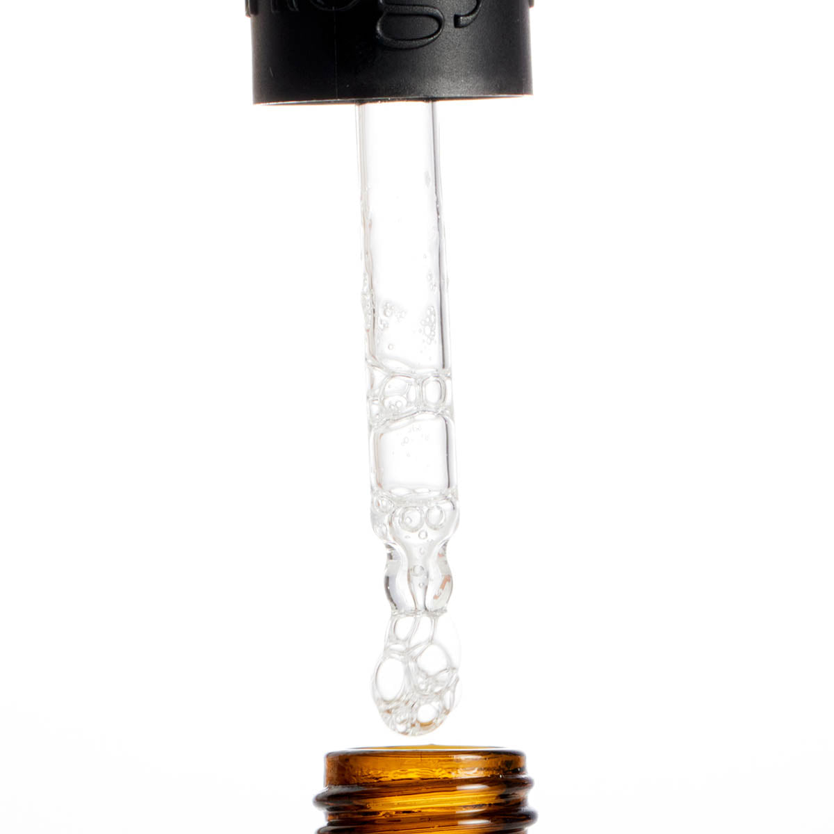 Close-up of a glass dropper with a black cap and amber base on a white background
