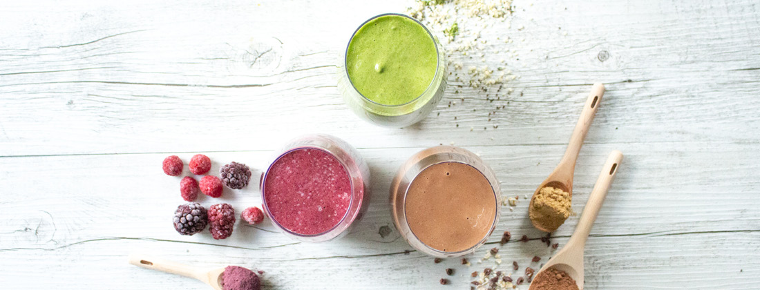 Aerial view of 3 summer smoothies surrounded by healthy ingredients