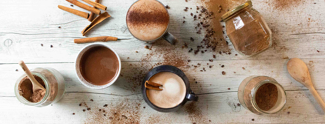 Close up of cacao ingredients to make hot beverage on white wooden table