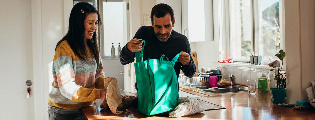 Couple happily puts groceries away from reusable bag