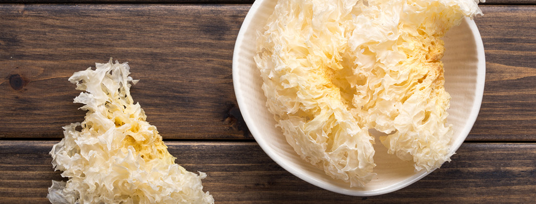 Close up of Tremella mushrooms in a bowl and on a wooden table