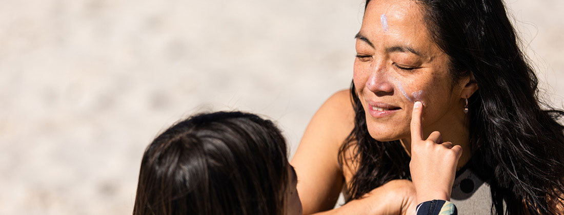 Daughter applies sun protection cream on her mother 