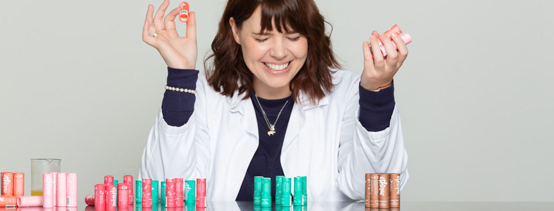 Ethique's Brianne West smiles with Ethique lip balms