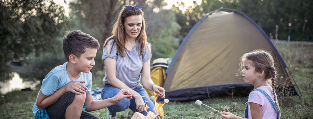 Family Gathered Around Campfire Roasting Marshmallows On A Stick 